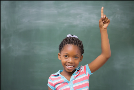 black girl with hand up in front of blackboard